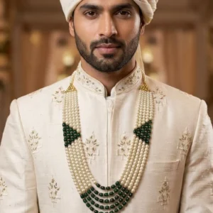 Indian groom wearing a traditional five-layered white pearl and green bead mala with a cream sherwani and safa
