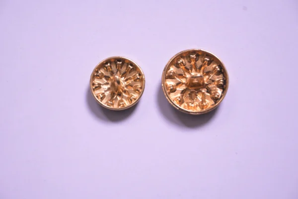 Close-up view of vintage gold floral metal buttons arranged on a clean background