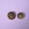 Macro shot showing intricate floral etching and antique gold finish on designer garment buttons
