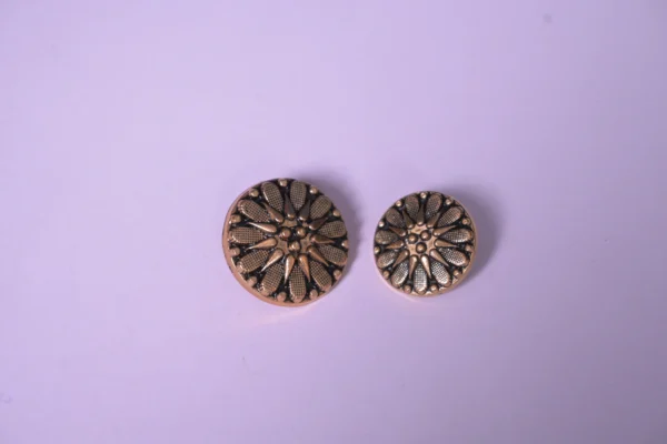 Macro shot showing intricate floral etching and antique gold finish on designer garment buttons